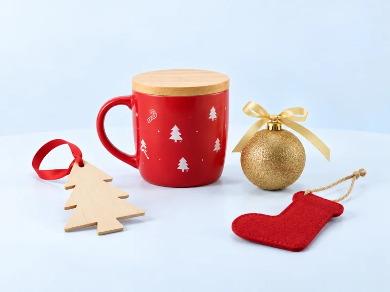 Christmas composition with a red mug, wooden tree ornament, gold bauble and red stocking